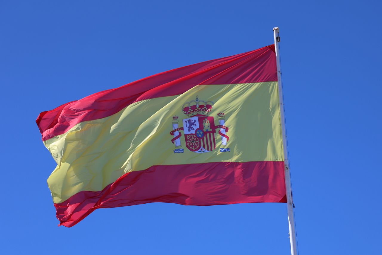 gallery-4 Vibrant Spanish flag waving in Cádiz, Spain, set against a bright blue sky.