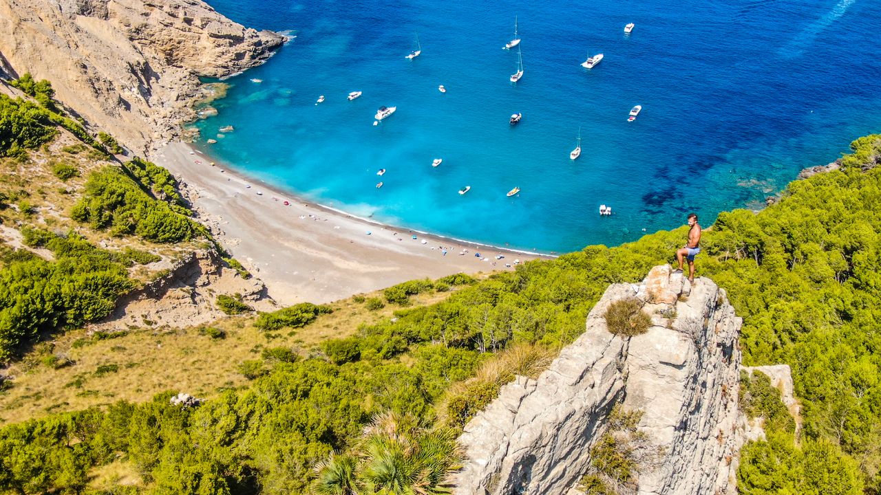 gallery-2 Aerial view of a scenic beach and cliffside with clear blue waters, perfect for travel and adventure.